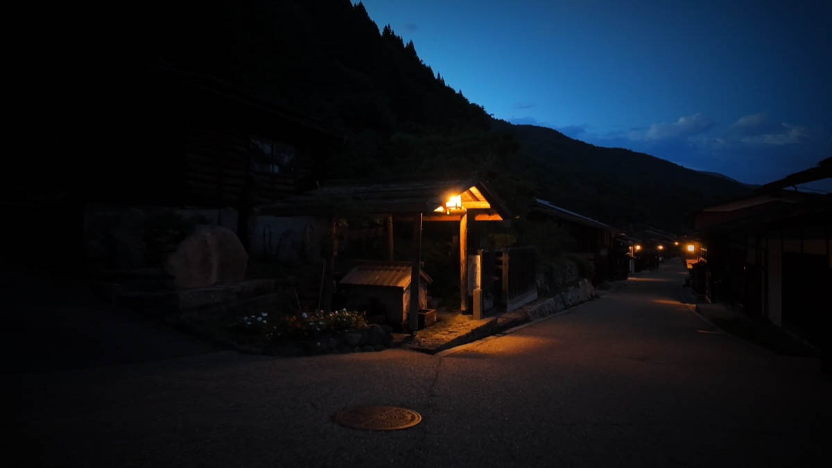 道端の木の小屋と、山のシルエット