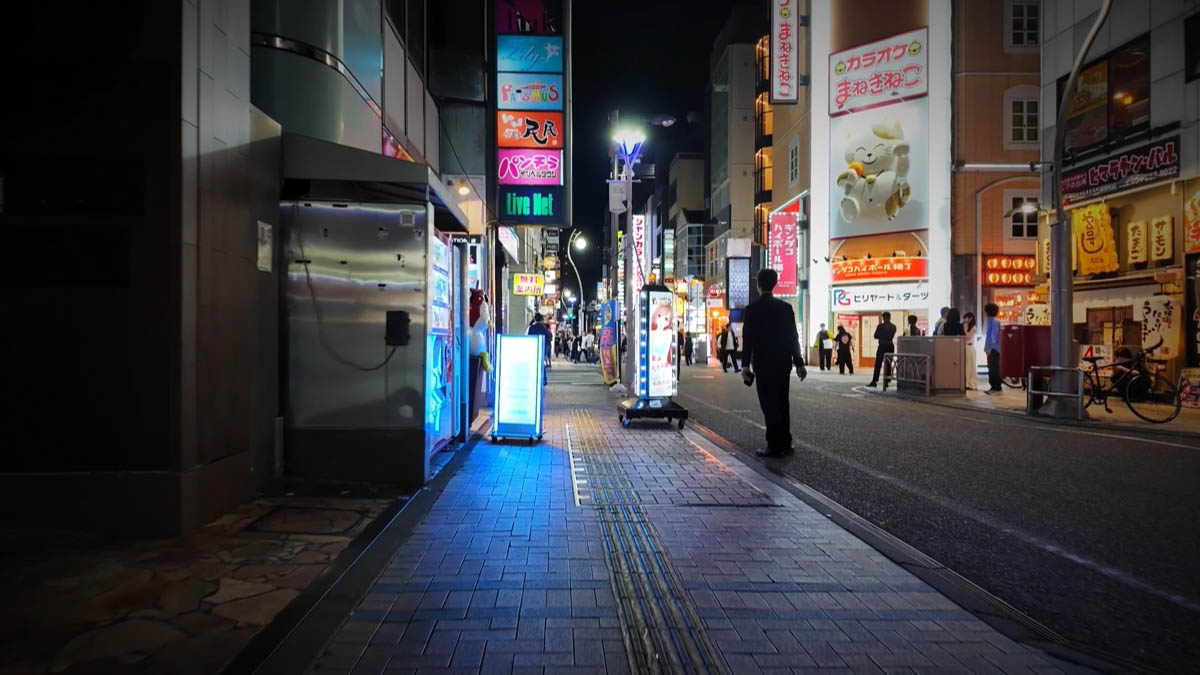 カラオケ通りの角 まねきねこの看板と、縦に積まれたネオン