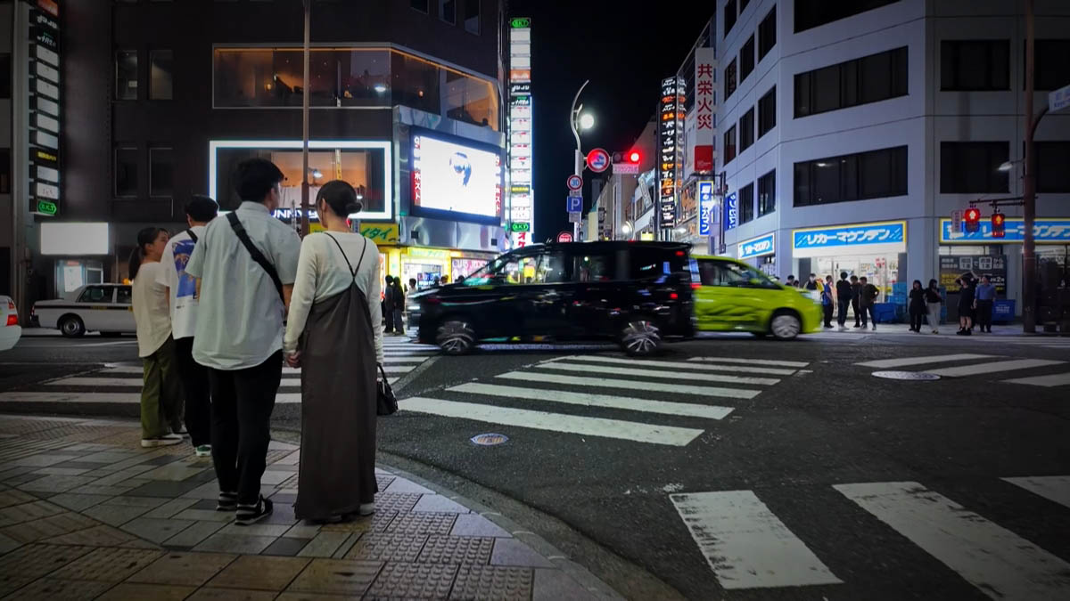 繁華街の交差点 リカーマウンテンの看板と、交差点を走る車